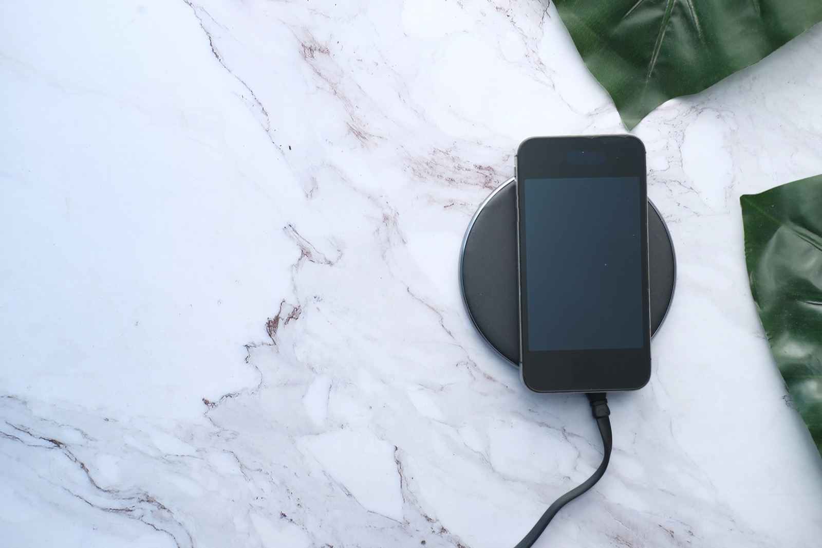 A smartphone charging on a wireless charging pad