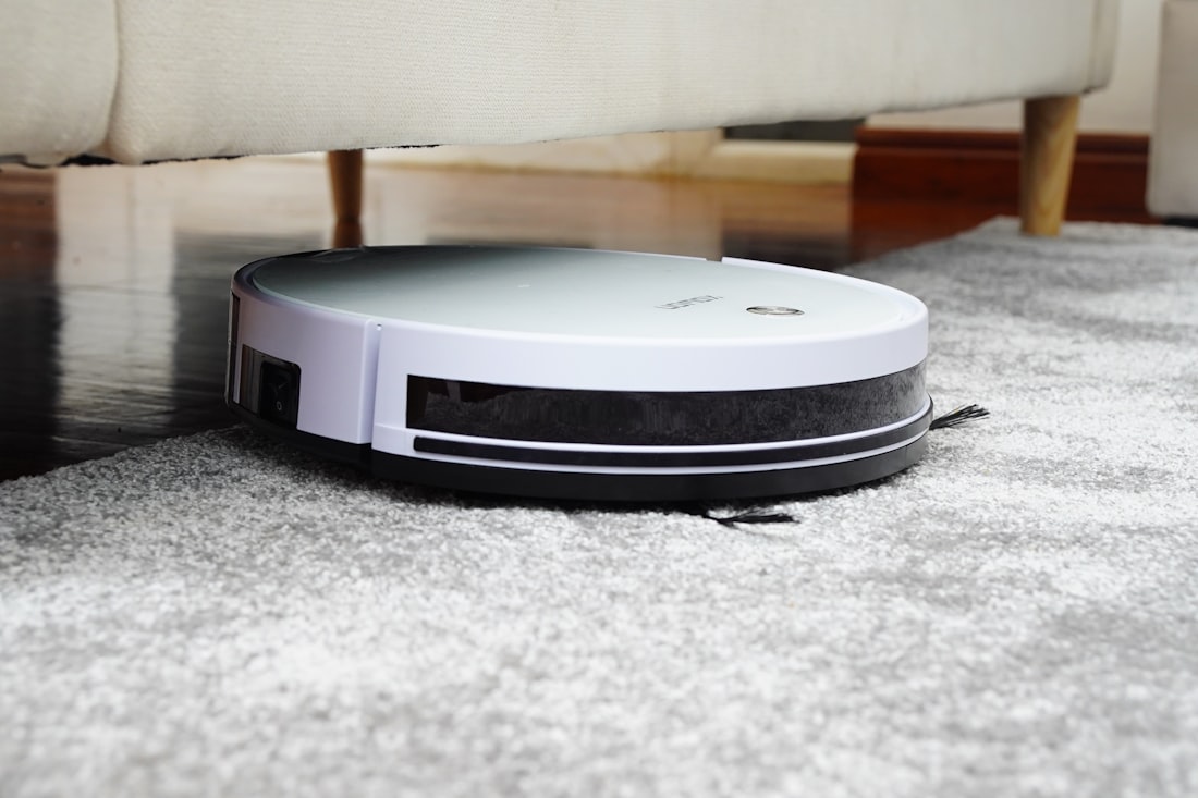 A budget upright vacuum cleaning a low-pile rug on a hard floor