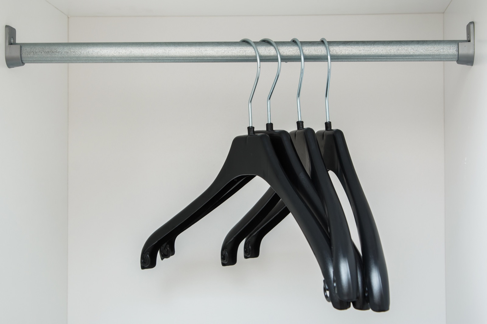 Black plastic clothes hangers on a closet rod