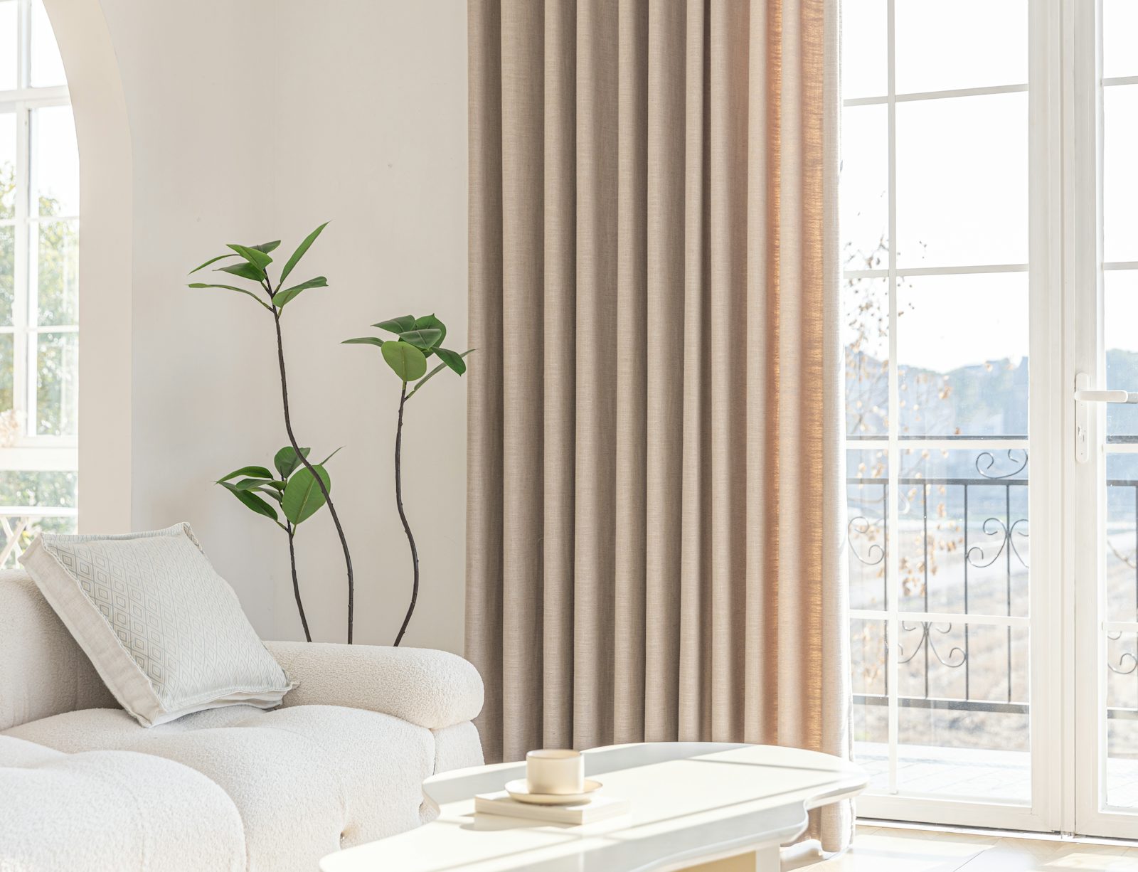 Bright living room with full-length neutral curtains framing a large window