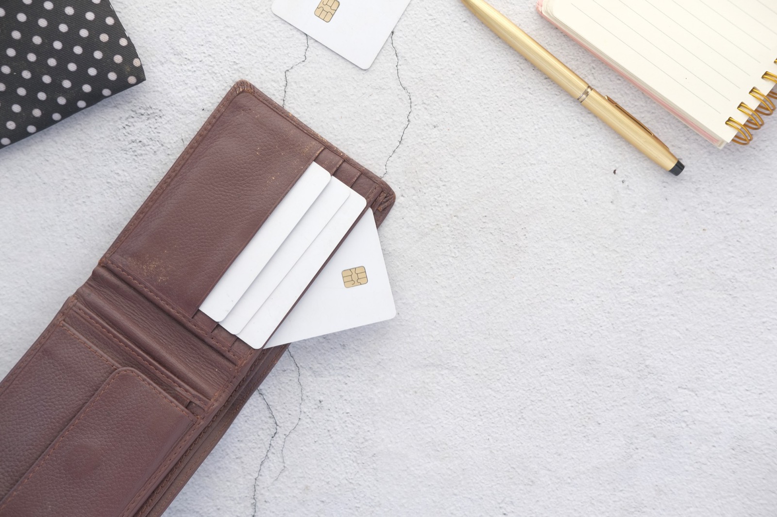 Cards being pulled from a slim leather wallet on a desk