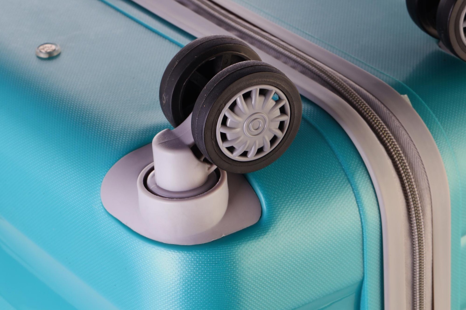 Close-up of a hardside suitcase spinner wheel assembly mounted at the corner
