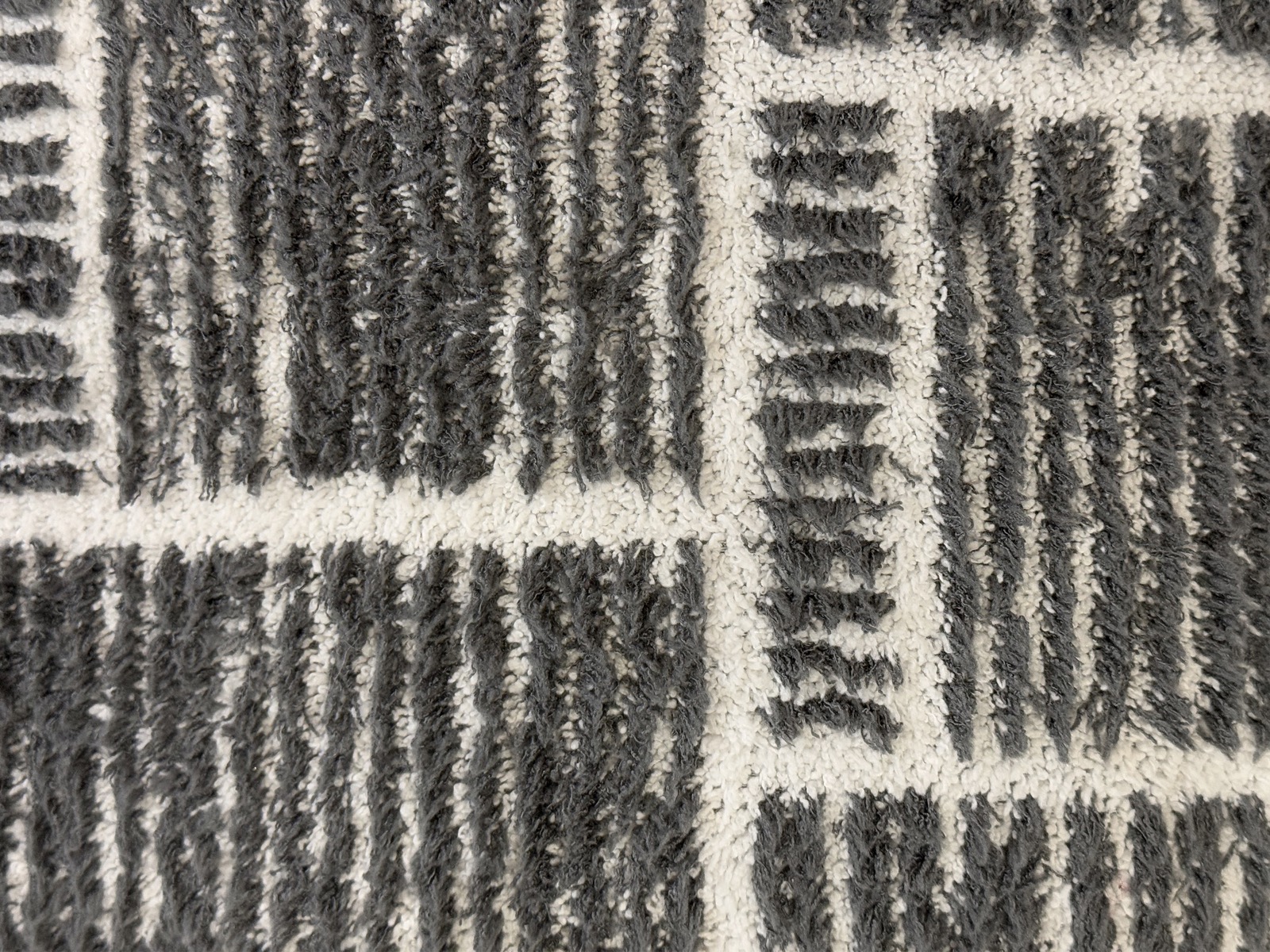 Close-up of a low-pile area rug surface showing its dense geometric pile