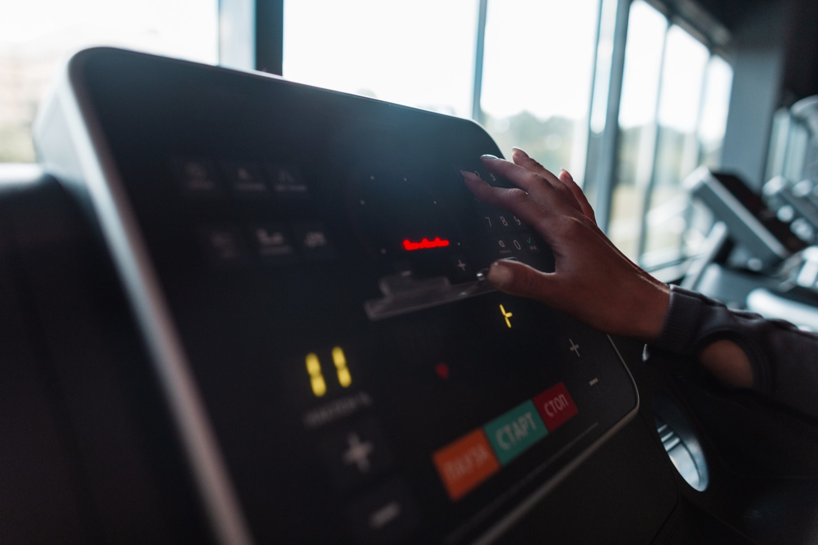 Close view of a hand adjusting the speed controls on a treadmill display panel