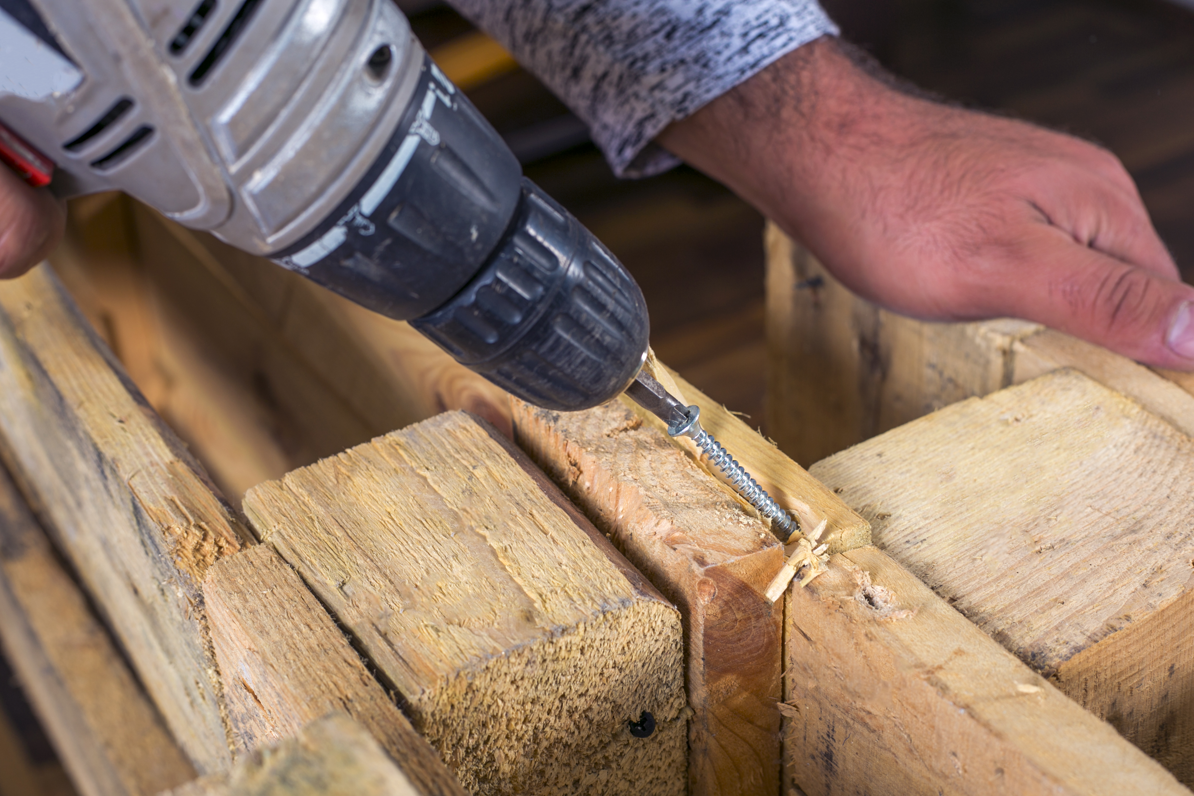 Cordless drill driver with visible clutch collar driving a screw into a wood board