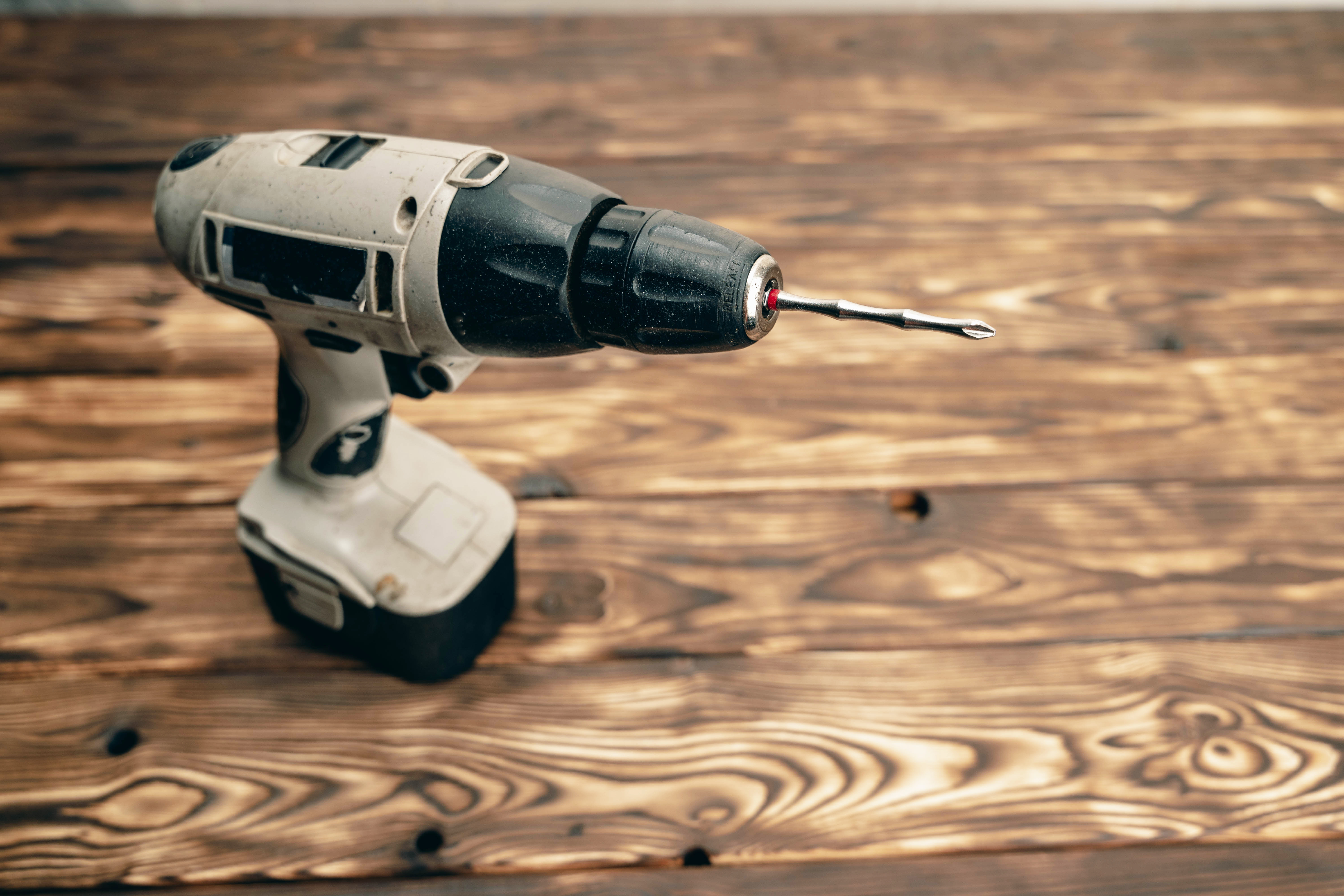 Cordless drill with a drill bit resting on a wooden workbench