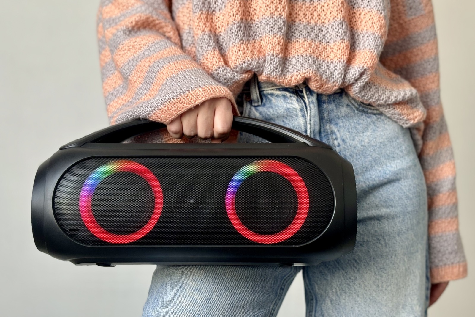 Large boombox-style portable Bluetooth party speaker with light-up drivers carried by hand