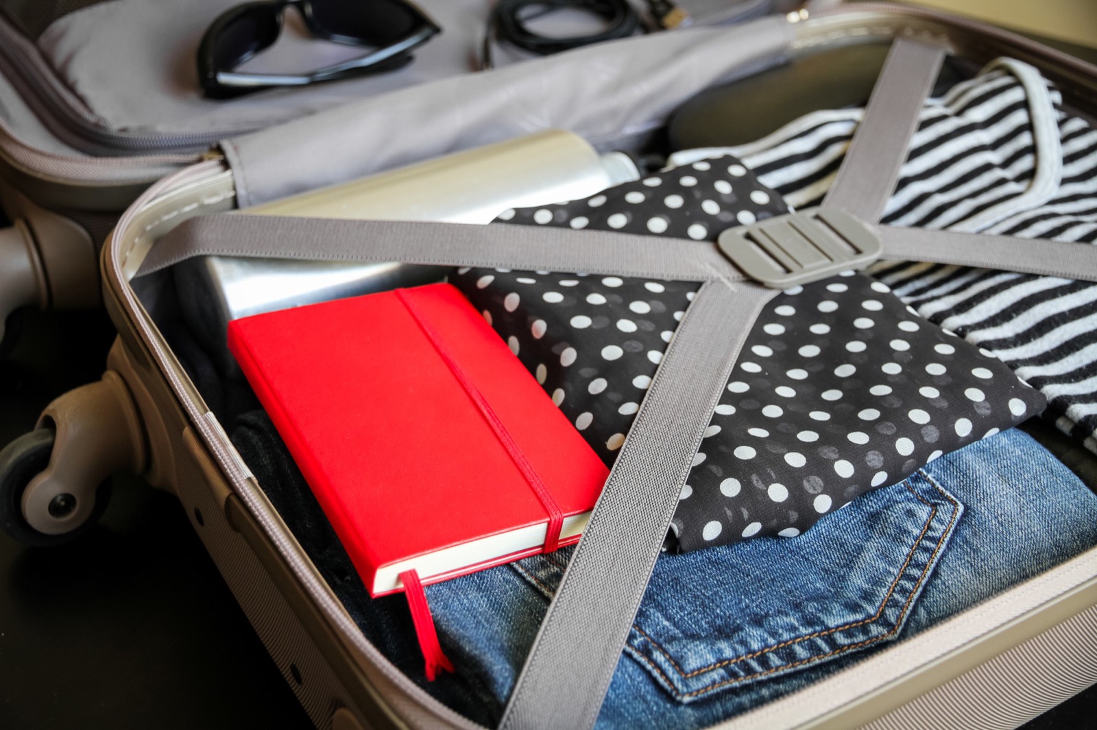 Open hardside suitcase interior with elastic packing straps holding folded clothes
