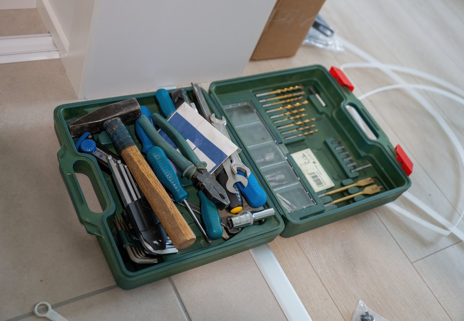 Open household tool case with hand tools and a tray of drill bits