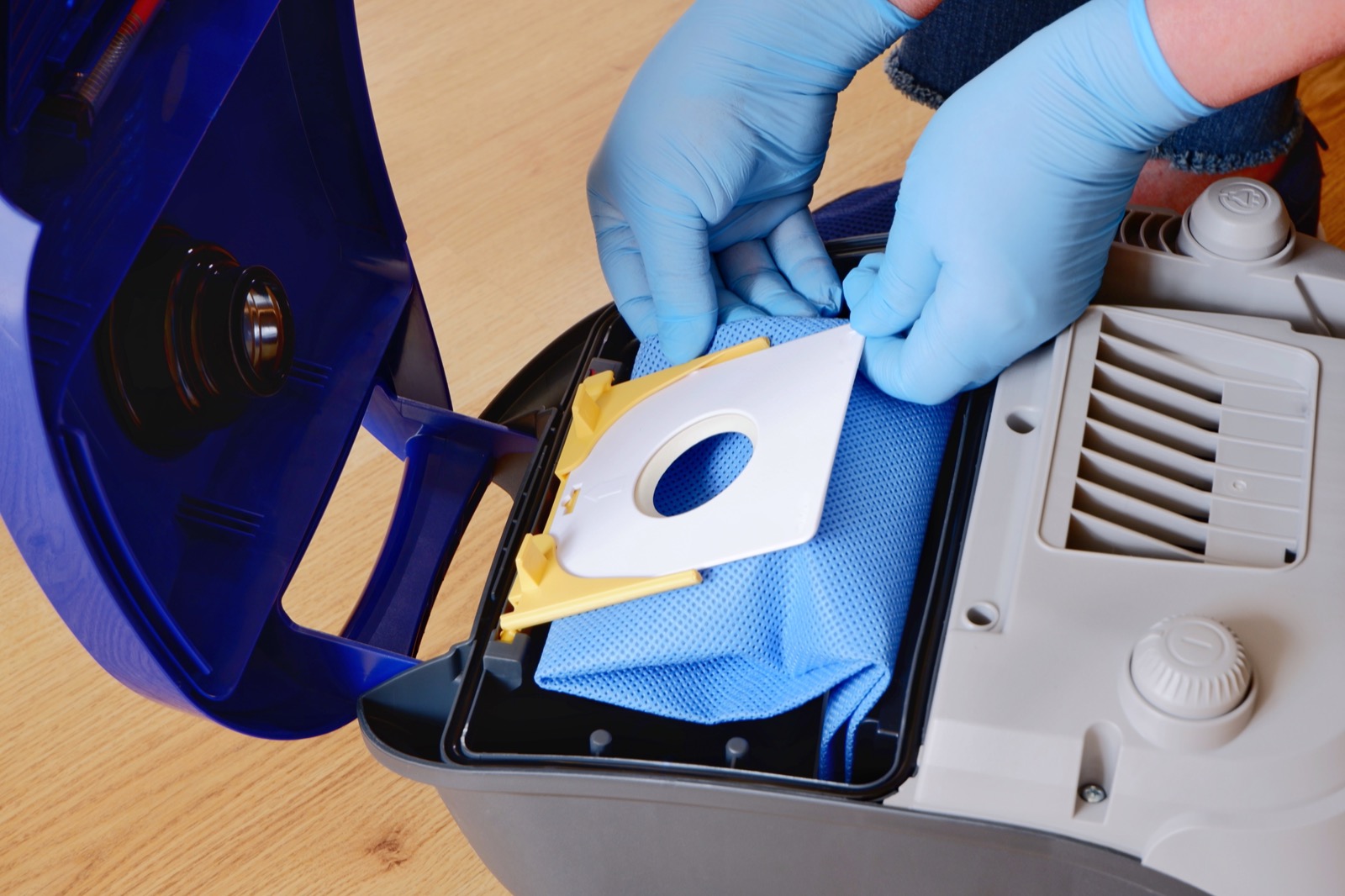 Replacement dust bag being installed in a bagged canister vacuum