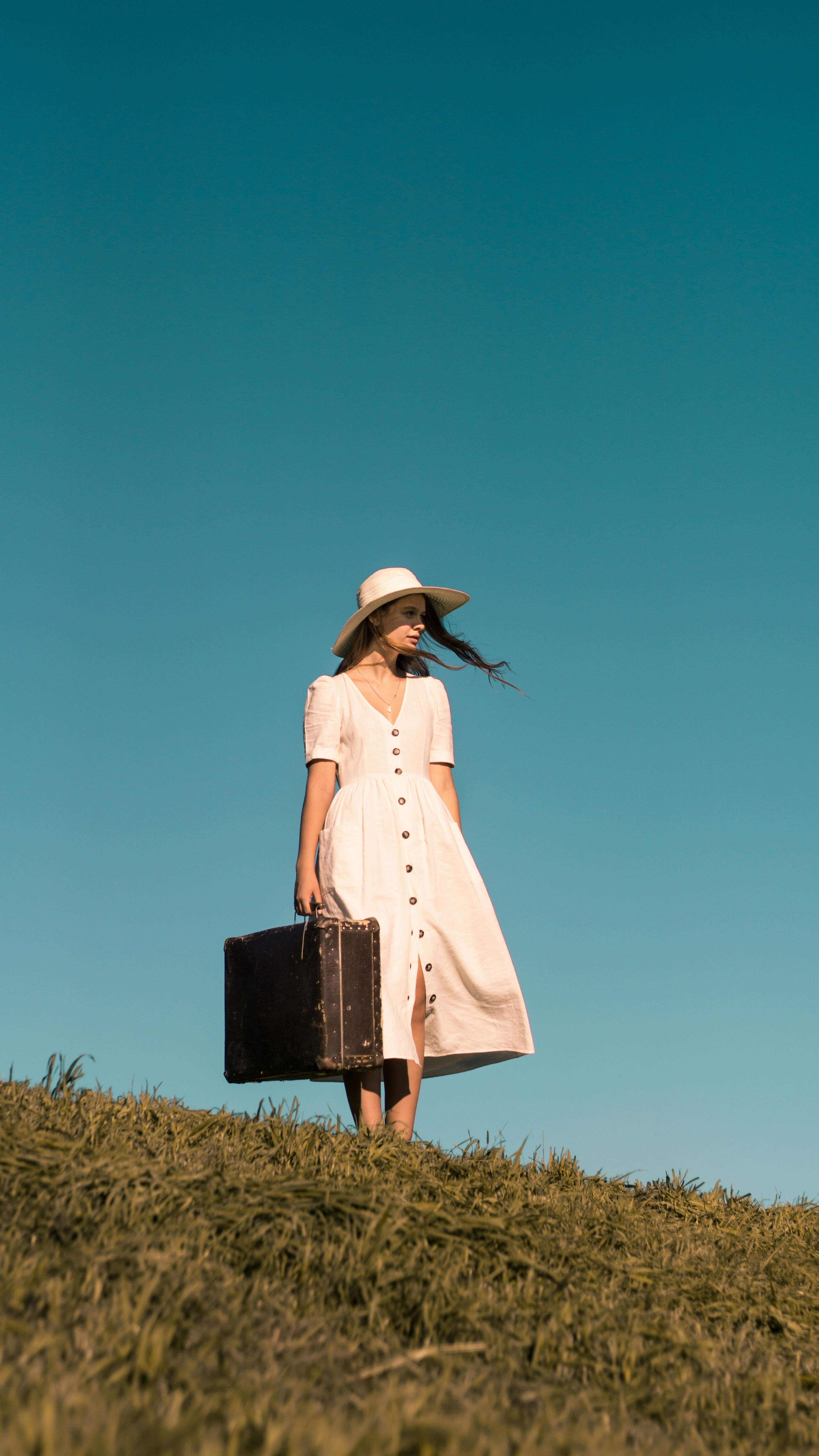Two women in light summer dresses walking outdoors on a sunny day